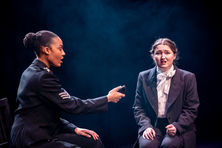 2 people on stage lit whilst interviewing,